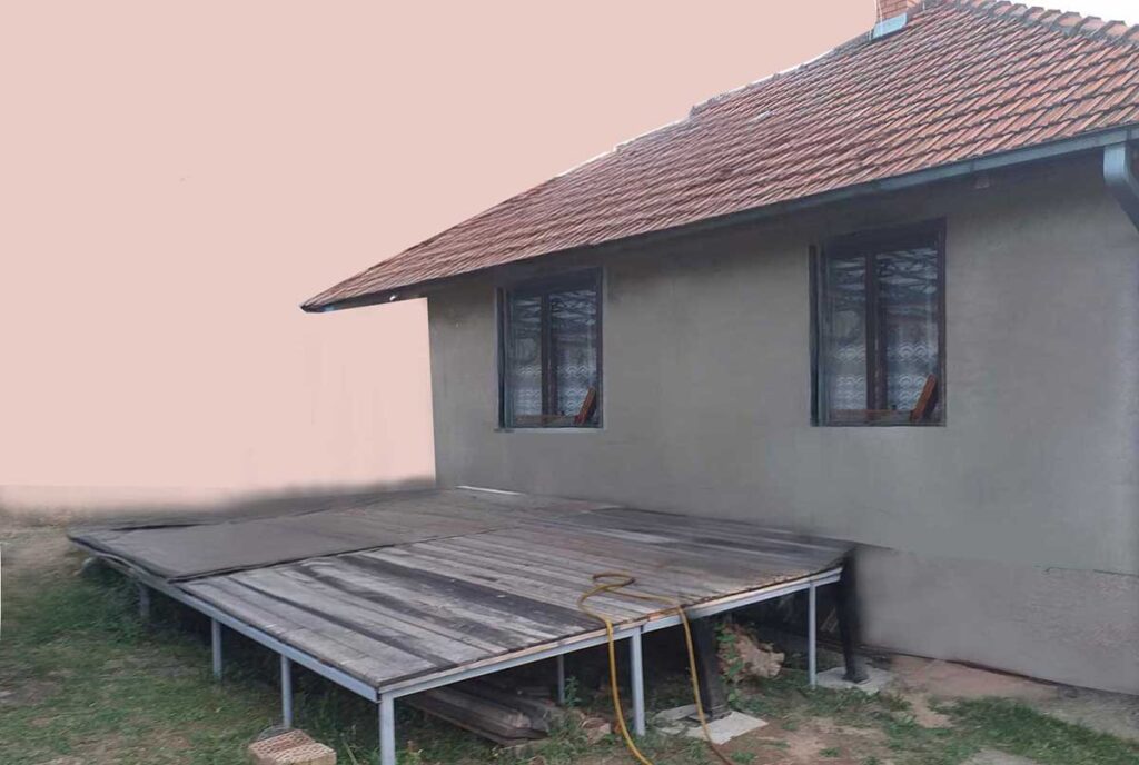 Completed level deck built on a sloped yard: Wood decking boards cover the metal frame, providing access down the 12-inch (30 cm) elevation drop
